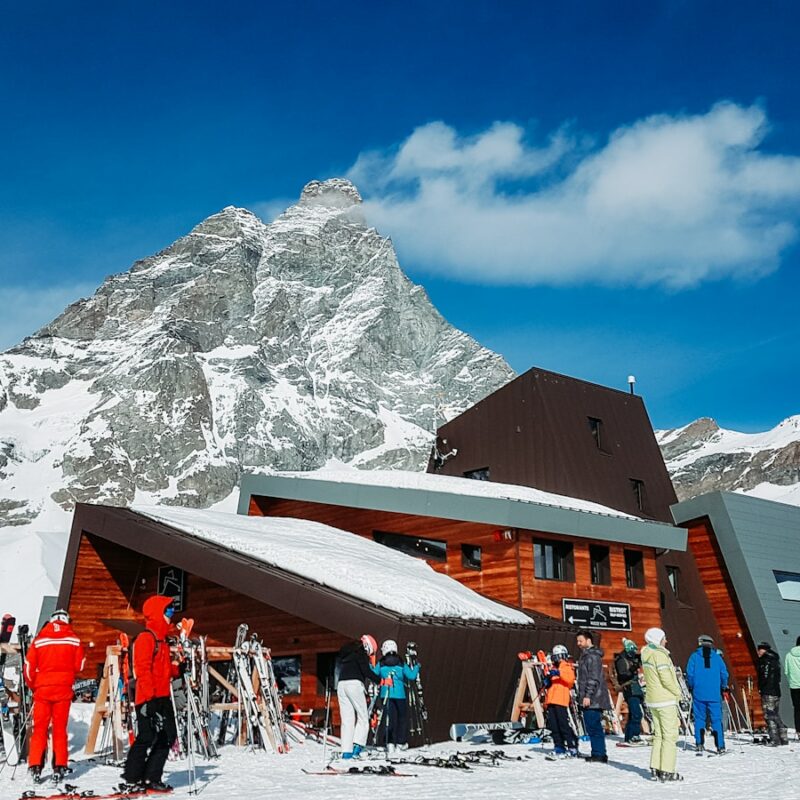 people standing on snow covered ground near brown wooden house during daytime